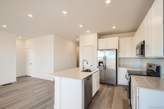 kitchen featuring an island with sink, sink, white cabinets, light hardwood / wood-style floors, and stainless steel appliances