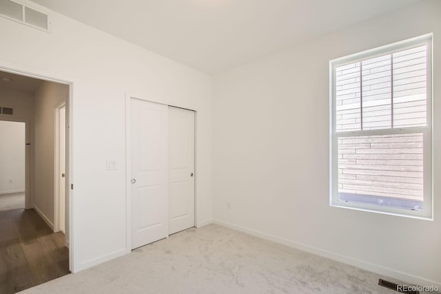 unfurnished bedroom featuring a closet, light carpet, and multiple windows