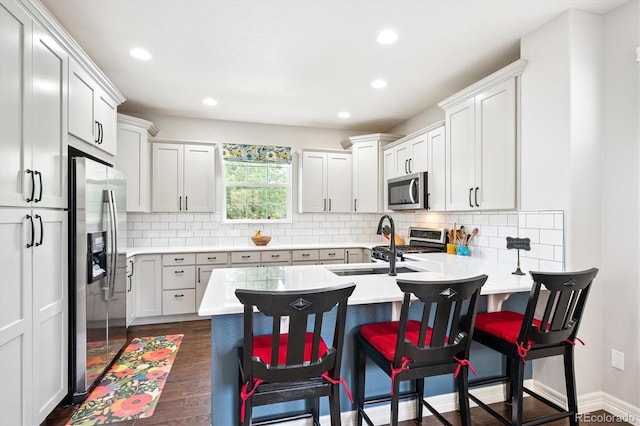 9311 E 5th Ave, Denver, CO 80230 - kitchen with appliances with stainless steel finishes, a peninsula, dark wood-type flooring, a breakfast bar, and light countertops