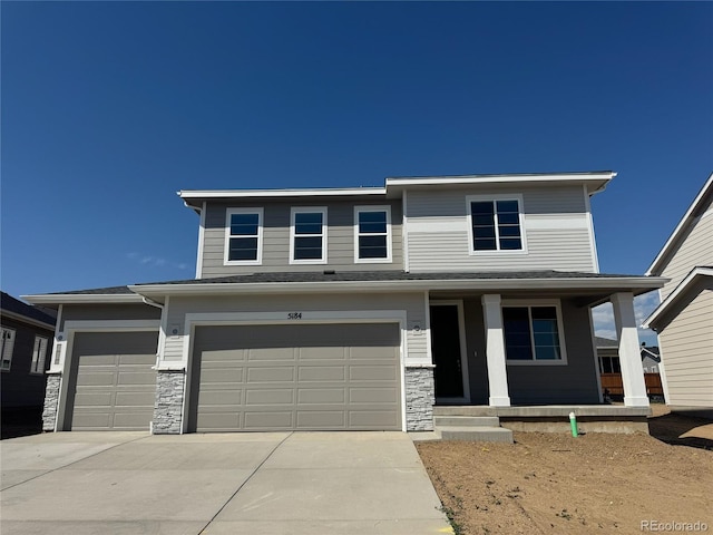 5184 Brangus Dr, Windsor, CO 80528 - view of front of home featuring stone siding, covered porch, concrete driveway, and an attached garage