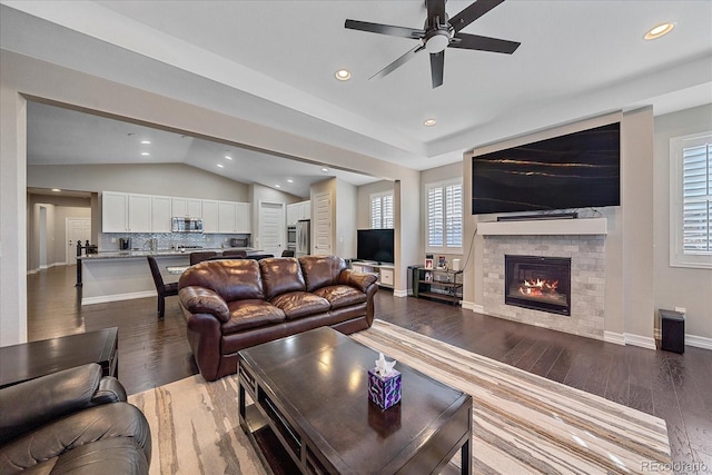 living room with ceiling fan, dark wood-type flooring, and vaulted ceiling