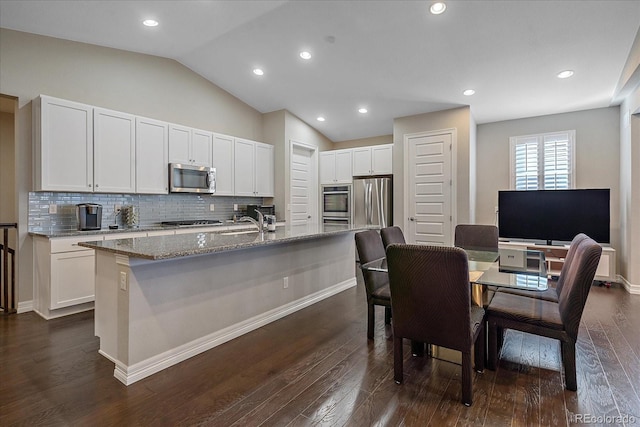 kitchen featuring a kitchen island with sink, dark wood-type flooring, light stone counters, white cabinetry, and stainless steel appliances