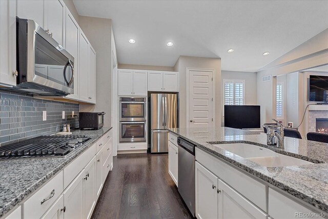 kitchen with white cabinets, sink, light stone countertops, dark hardwood / wood-style flooring, and stainless steel appliances