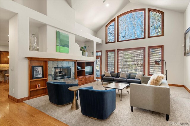5350 S Marshall St, Littleton, CO 80123 - living area with baseboards, high vaulted ceiling, plenty of natural light, light wood-style floors, and a tiled fireplace