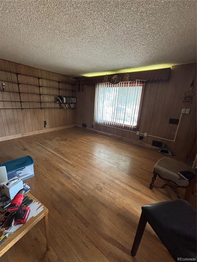 interior space featuring wooden walls, wood finished floors, and a textured ceiling