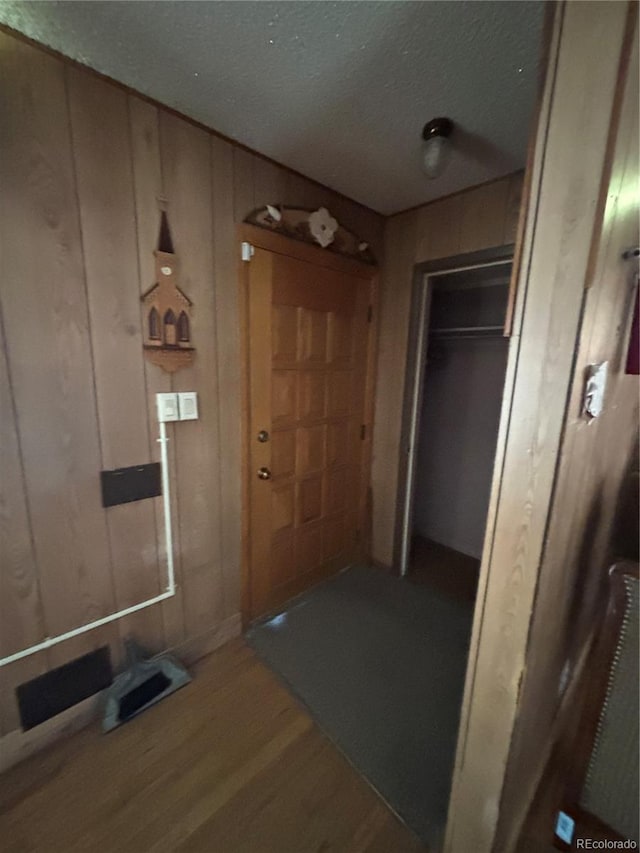 corridor featuring wood finished floors and wood walls