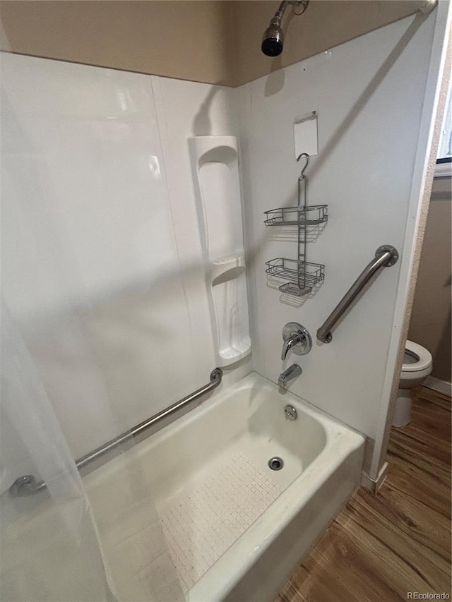 bathroom featuring toilet, washtub / shower combination, and wood finished floors
