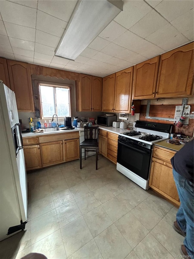 kitchen featuring light countertops, stainless steel microwave, gas stove, white fridge with ice dispenser, and brown cabinets