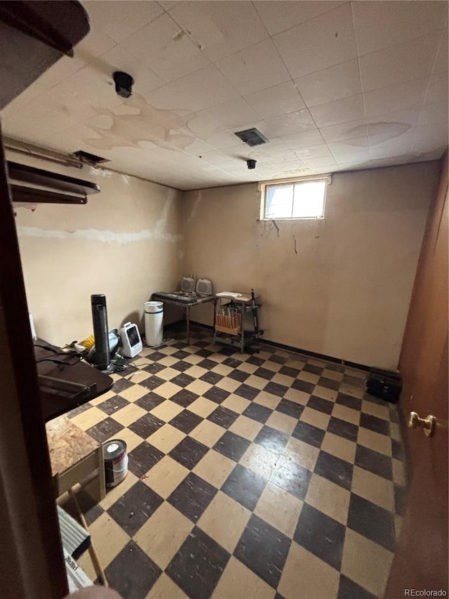 below grade area with a paneled ceiling, tile patterned floors, and visible vents