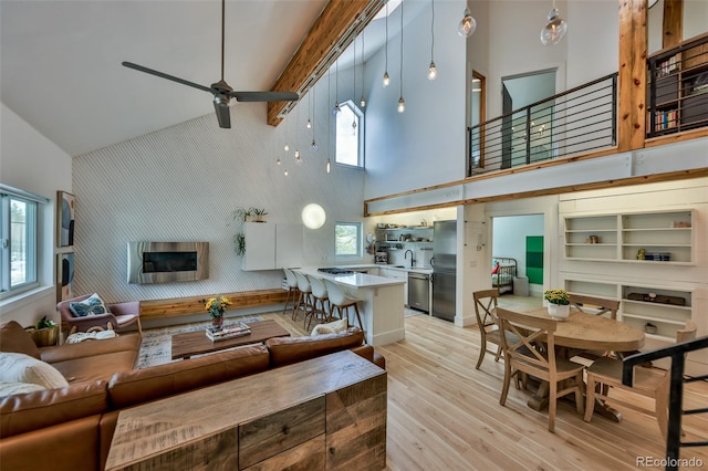 living room featuring high vaulted ceiling, plenty of natural light, sink, and light hardwood / wood-style floors