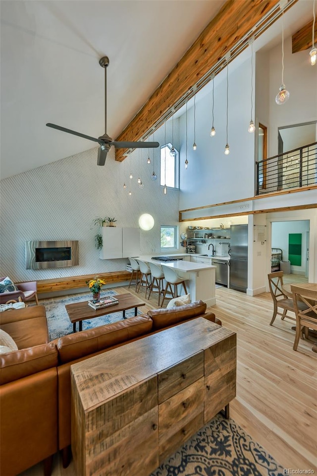 living room with high vaulted ceiling, ceiling fan, and light wood-type flooring