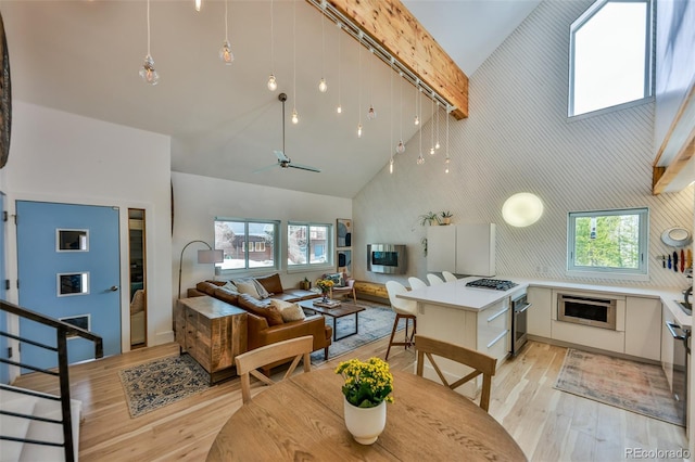 kitchen featuring light wood-type flooring, ceiling fan, white cabinetry, and high vaulted ceiling