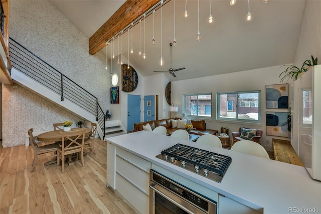 kitchen with light hardwood / wood-style floors, ceiling fan, appliances with stainless steel finishes, vaulted ceiling with beams, and pendant lighting