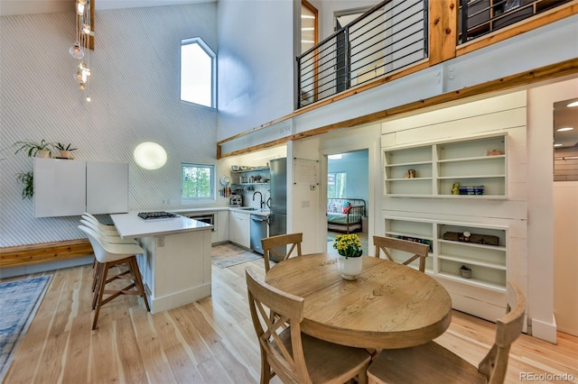 dining space with light hardwood / wood-style flooring, a high ceiling, and sink