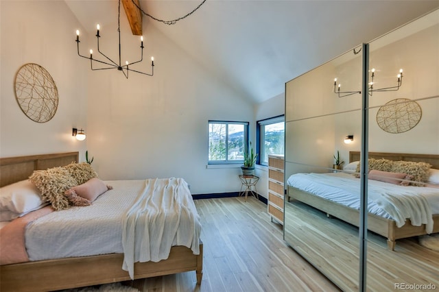 bedroom featuring high vaulted ceiling, hardwood / wood-style floors, and a notable chandelier