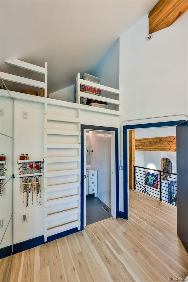 unfurnished bedroom featuring wood-type flooring and a towering ceiling