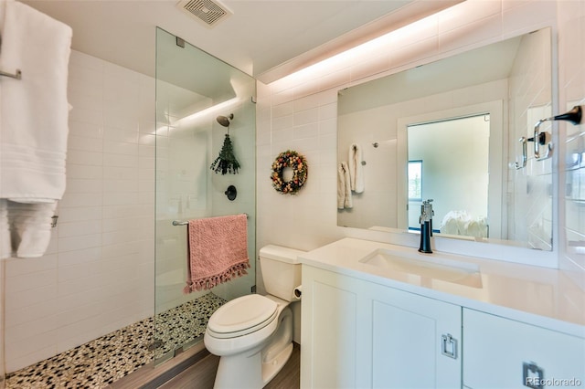 bathroom featuring toilet, a shower with shower door, and vanity