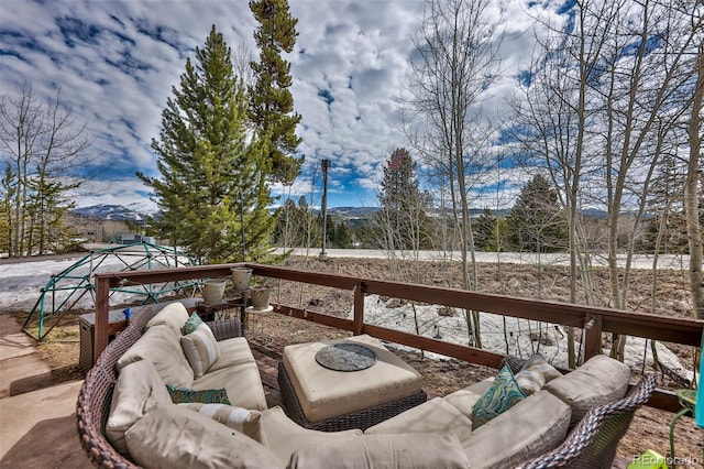 snow covered deck featuring outdoor lounge area and a mountain view