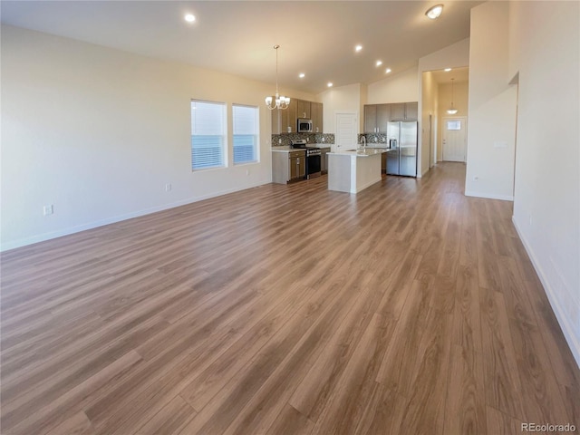 unfurnished living room featuring lofted ceiling, sink, dark hardwood / wood-style floors, and a chandelier