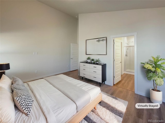 bedroom with connected bathroom, light hardwood / wood-style flooring, and high vaulted ceiling