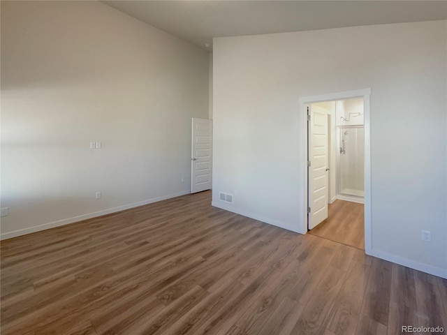 unfurnished bedroom with a high ceiling, dark hardwood / wood-style flooring, and ensuite bath