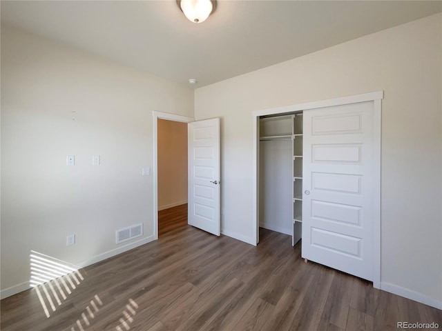 unfurnished bedroom with dark hardwood / wood-style flooring and a closet