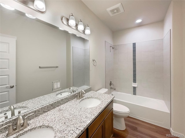 full bathroom with vanity, toilet, tiled shower / bath combo, and hardwood / wood-style floors