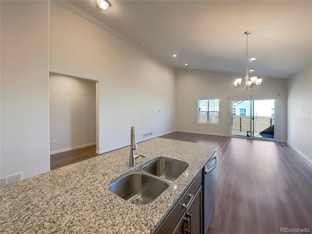 kitchen with pendant lighting, sink, a notable chandelier, light stone countertops, and stainless steel dishwasher