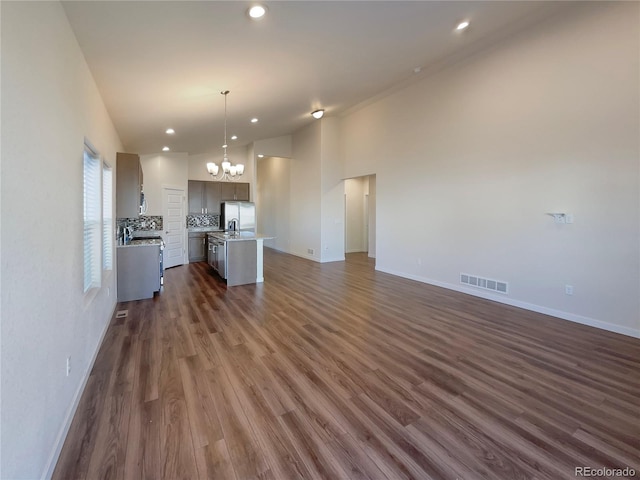 interior space with an inviting chandelier, appliances with stainless steel finishes, a kitchen island, pendant lighting, and decorative backsplash