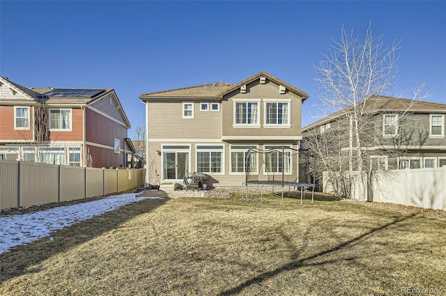 back of property with a patio, a lawn, and a trampoline