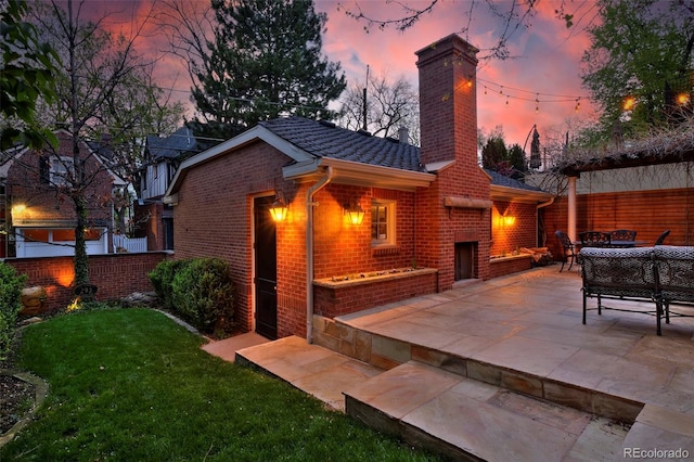 535 N High St, Denver, CO 80218 - back of property at dusk featuring brick siding, a chimney, a fireplace, and a patio area