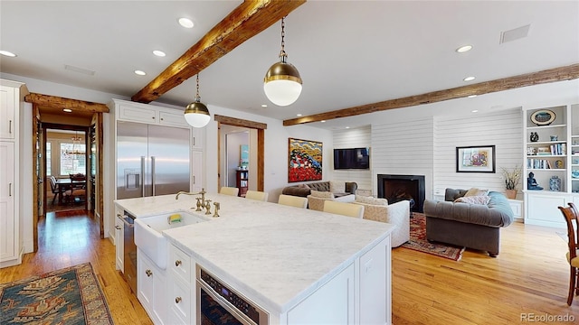 535 N High St, Denver, CO 80218 - kitchen with beamed ceiling, light wood-type flooring, a sink, recessed lighting, and white cabinetry