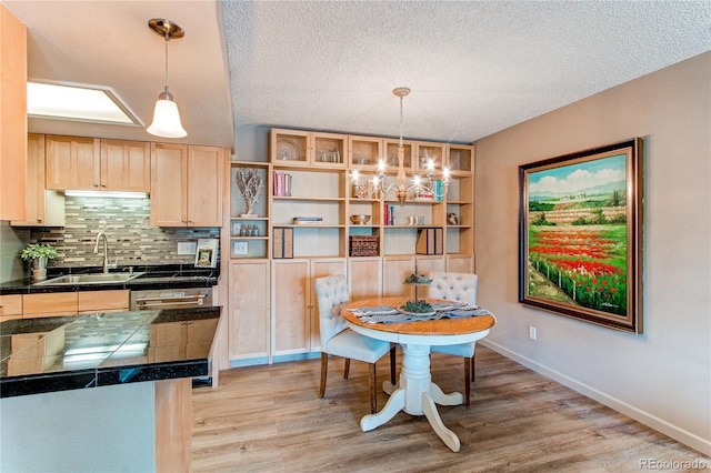 dining space with an inviting chandelier, light hardwood / wood-style flooring, sink, and a textured ceiling