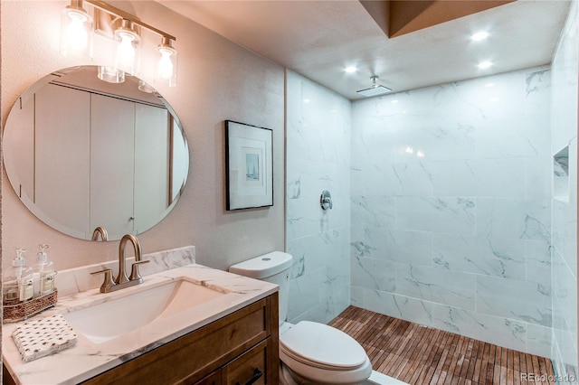 bathroom featuring vanity, tiled shower, and toilet