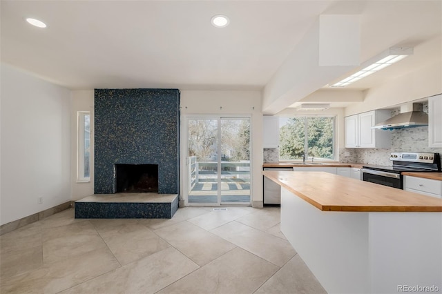 kitchen with sink, wooden counters, appliances with stainless steel finishes, white cabinets, and wall chimney exhaust hood