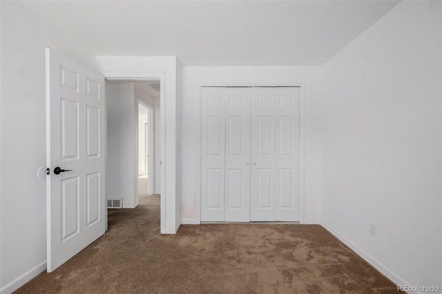 unfurnished bedroom featuring dark colored carpet and a closet