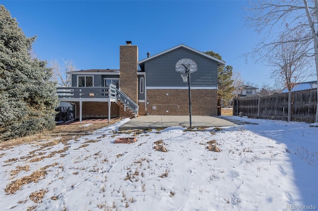 snow covered rear of property with a wooden deck