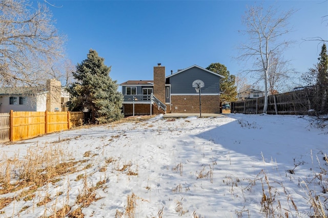 view of snow covered back of property