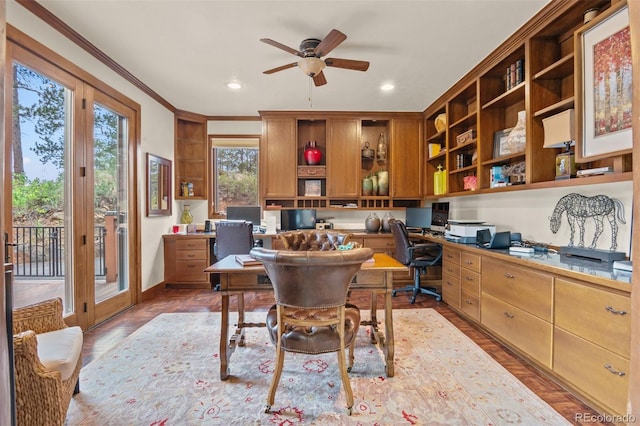 office with built in desk, ceiling fan, and crown molding