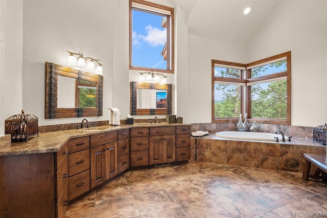 bathroom featuring tiled bath, vanity, and lofted ceiling