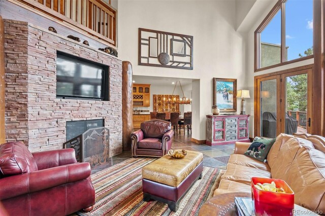 living room featuring a stone fireplace, a towering ceiling, and a chandelier