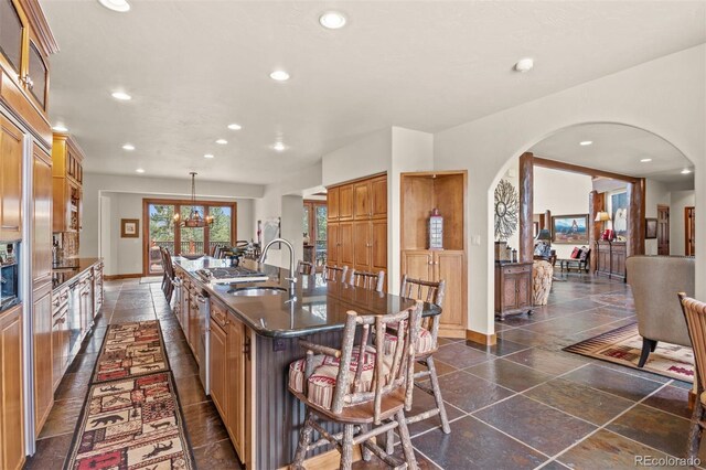 kitchen featuring sink, decorative light fixtures, a chandelier, a breakfast bar area, and an island with sink