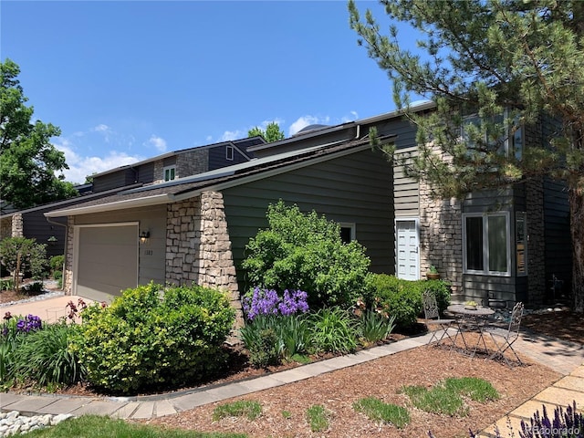 view of front of home with a garage, stone siding, and driveway