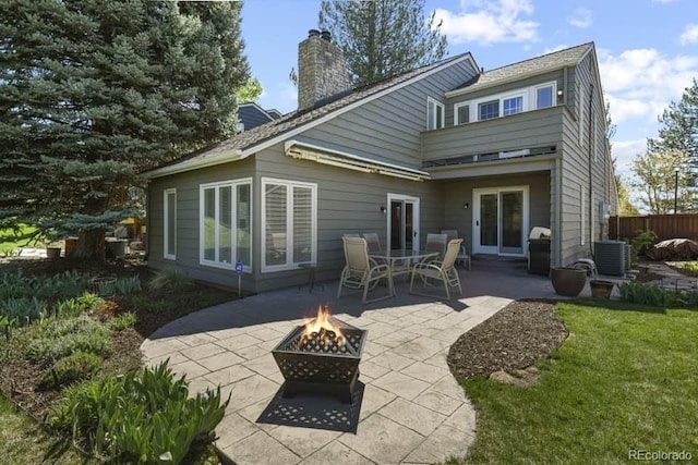 rear view of house featuring a patio, central AC unit, a fire pit, fence, and a chimney