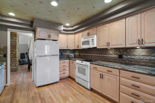 kitchen with white appliances, light wood-style floors, decorative backsplash, dark stone counters, and light brown cabinetry