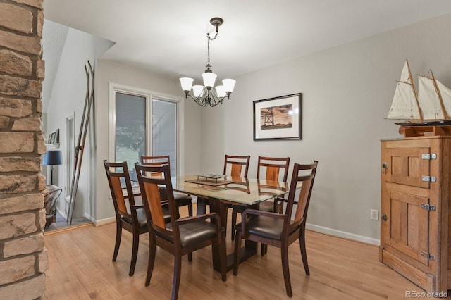 dining area with light wood-type flooring, baseboards, and a chandelier