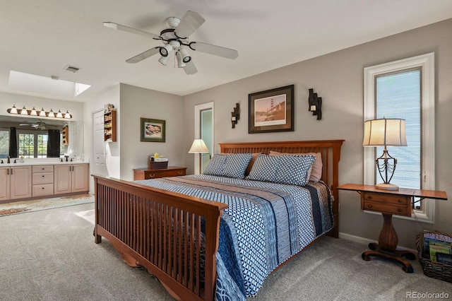 bedroom with light carpet, a skylight, visible vents, connected bathroom, and a sink