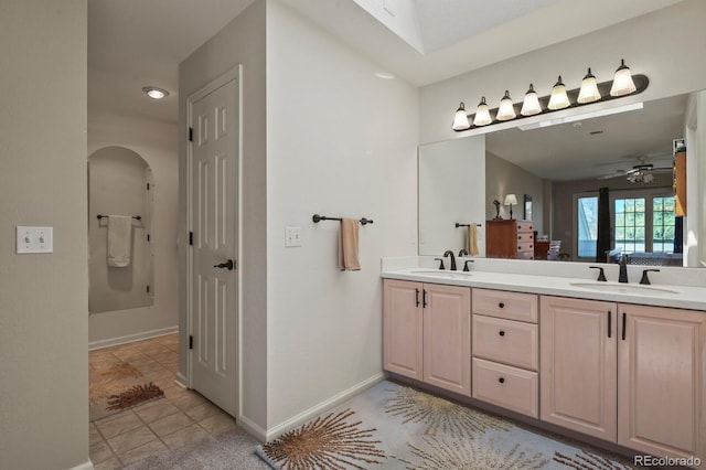 full bath with double vanity, a sink, a ceiling fan, and baseboards