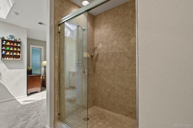 bathroom featuring a textured wall, a shower stall, and visible vents