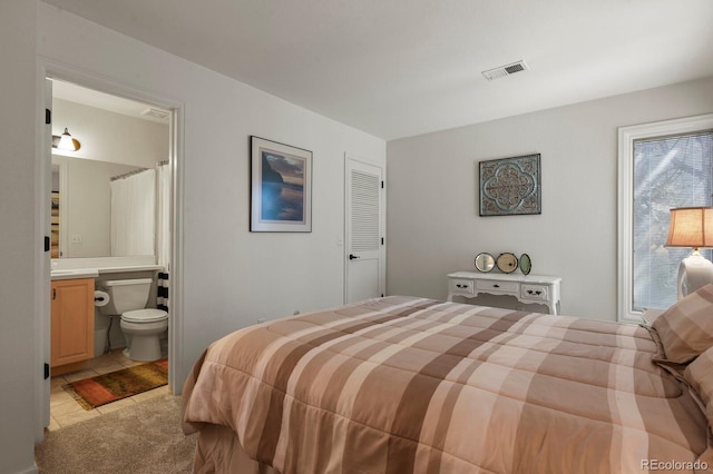 bedroom featuring visible vents, connected bathroom, and light colored carpet